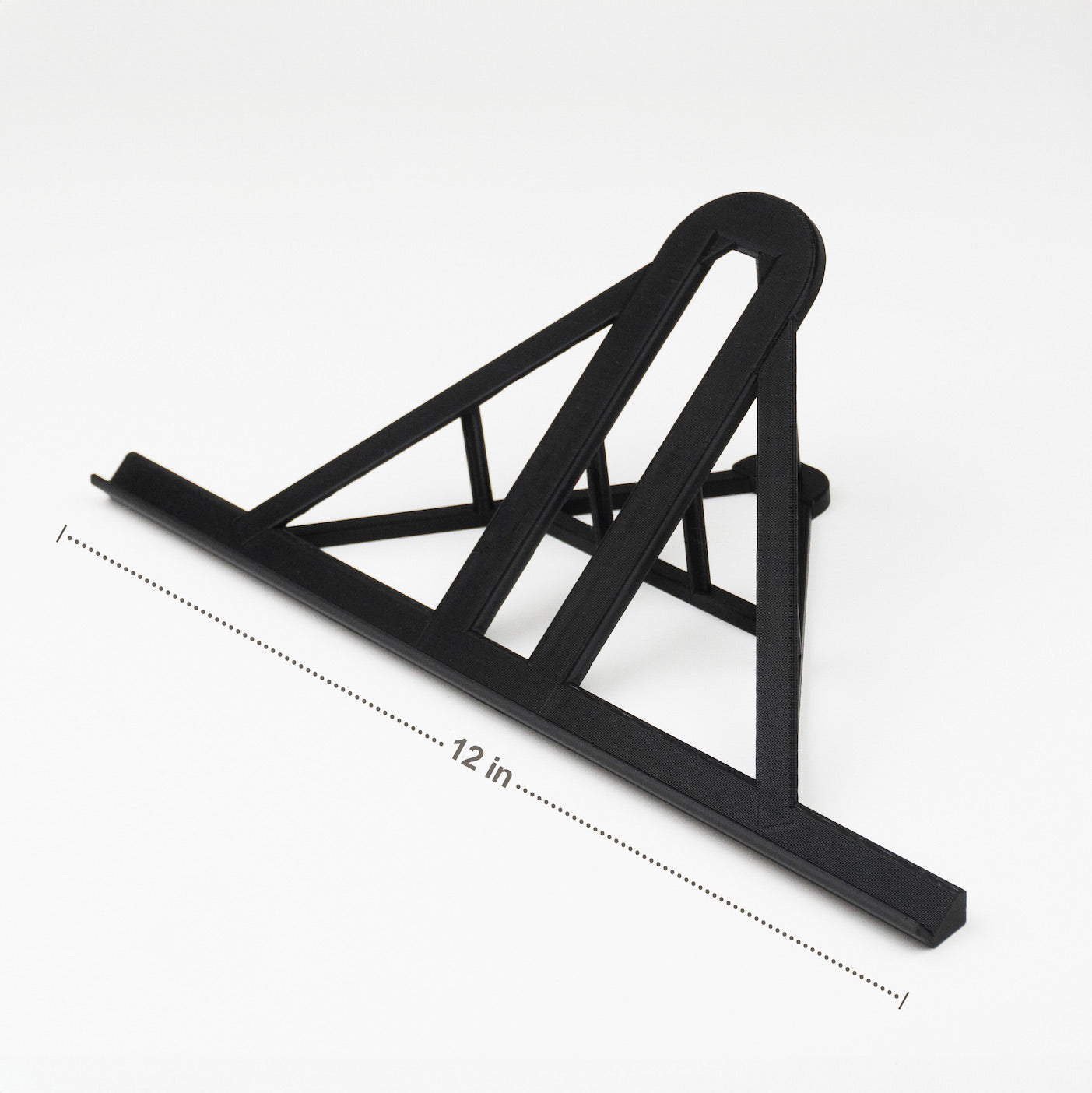 A black lego display stand with a slanted top, labeled "12 in" for scale, on a white surface.